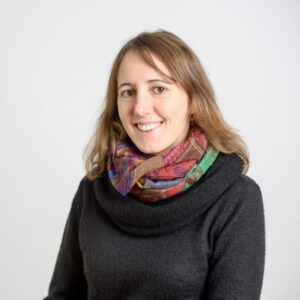 Foto von Dr, Astrid Gaida. Sie lächelt freundlich. Sie hat schulterlange hellbraune Haare und helle Haut. Sie trägt einen schwarzen Pulli und einen bunten Schal.