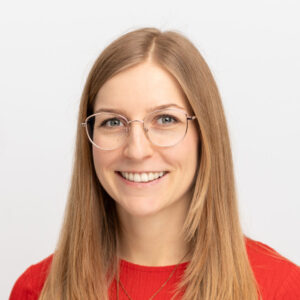 Foto von Heidi Wagner. Sie hat lange glatte blonde Haare, helle Haut und eine Brille. Sie lacht freundlich.
