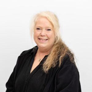 Foto von Heike Engelhardt. Sie lächelt freundlich, hat helle Haut und blonde, lockige, lange Haare. Sie trägt eine schwarze Bluse und eine Kette.