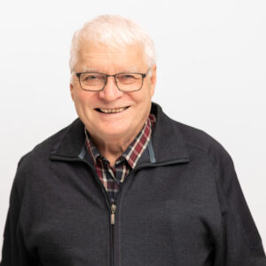 Foto von Dr. Joachim Kormannshaus. Er lächelt freundlich und hat weiße kurze Haare und helle Haut. Er trägt eine Brille und ein kariertes Hemd mit schwarzer Jacke.