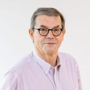 Foto von Dr. Lutz Brähler. Er lächelt freundlich und hat kurze fraue Haare. Er trägt ein hellrosa Hemd und eine markante dunkle Brille.