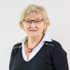 Foto von Dr. Marianne Luckner. Sie lächelt freundlich und hat blonde mittellange Haare und helle Haut. Sie trägt eine Brille, eine Kette und eine helle Bluse mit dunklem Pulli darüber.