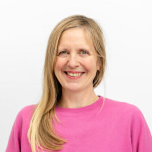 Foto: Nele Wilk. Sie hat helle Haut,blonde lange Haare, rosa Pulli und lächelt freundlich.