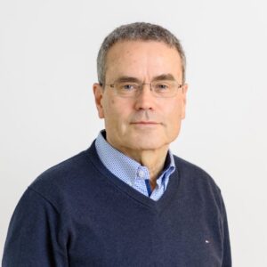 Foto von Dr. Niels Marg. Er lächelt leicht und har graue kurze Haare und helle Haut. Er trägt eine unscheinbare Brille und ein hellblaues Hemd mit dunkelblauem Pulli darüber.