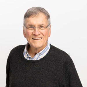 Foto von Dr. Otto Laakmann. Er lächelt freundlich und hat graue kurze Haare und helle Haut. Er trägt eine unscheinbare Brille und ein weiß-blaues Hemd mit Wollpulli darüber.